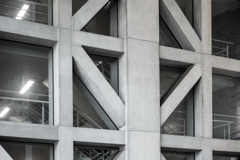 Close-up of a modern building's concrete structure featuring geometric patterns and large windows, illustrating construction techniques relevant to home energy efficiency and innovative design.