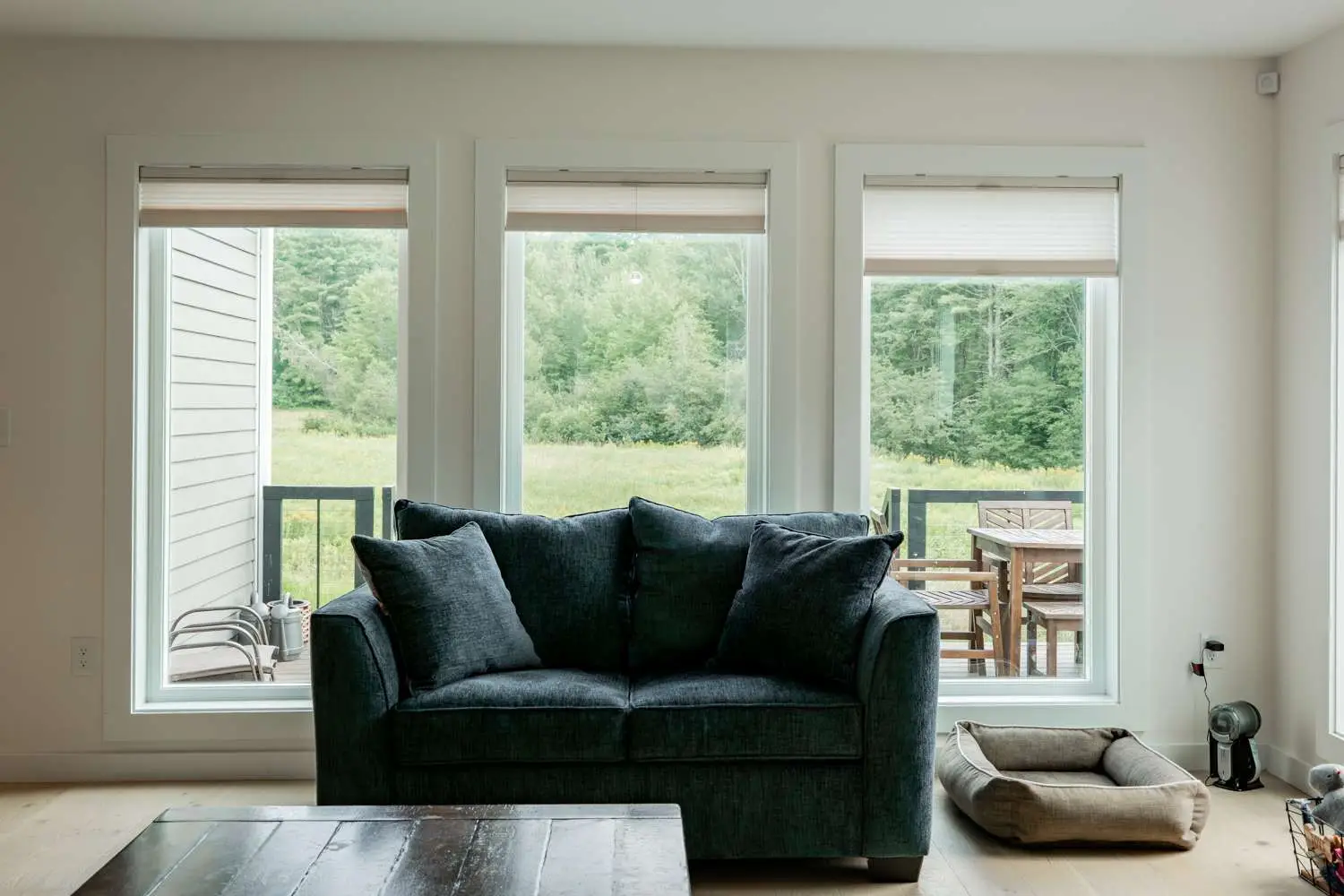 Cozy living room with dark sofa and large windows showcasing farmland views, emphasizing custom home design by Bradford Construction Management.