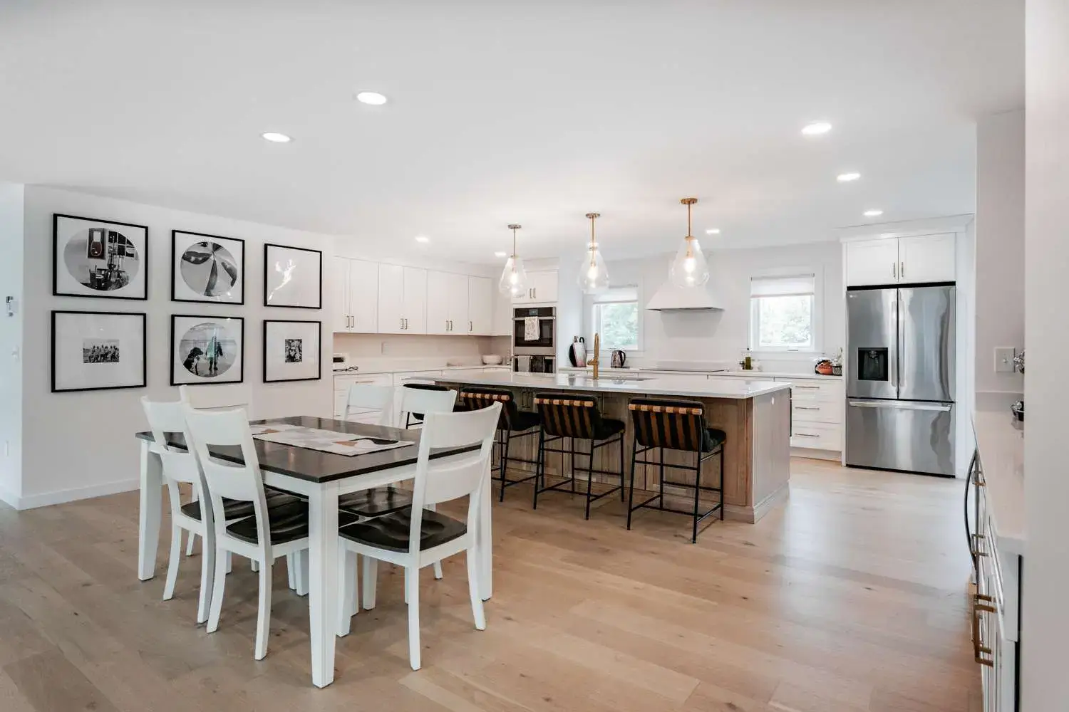 Modern kitchen interior featuring white cabinetry, a large island with bar seating, and a dining table, showcasing a clean design ideal for custom home projects by Bradford Construction Management.