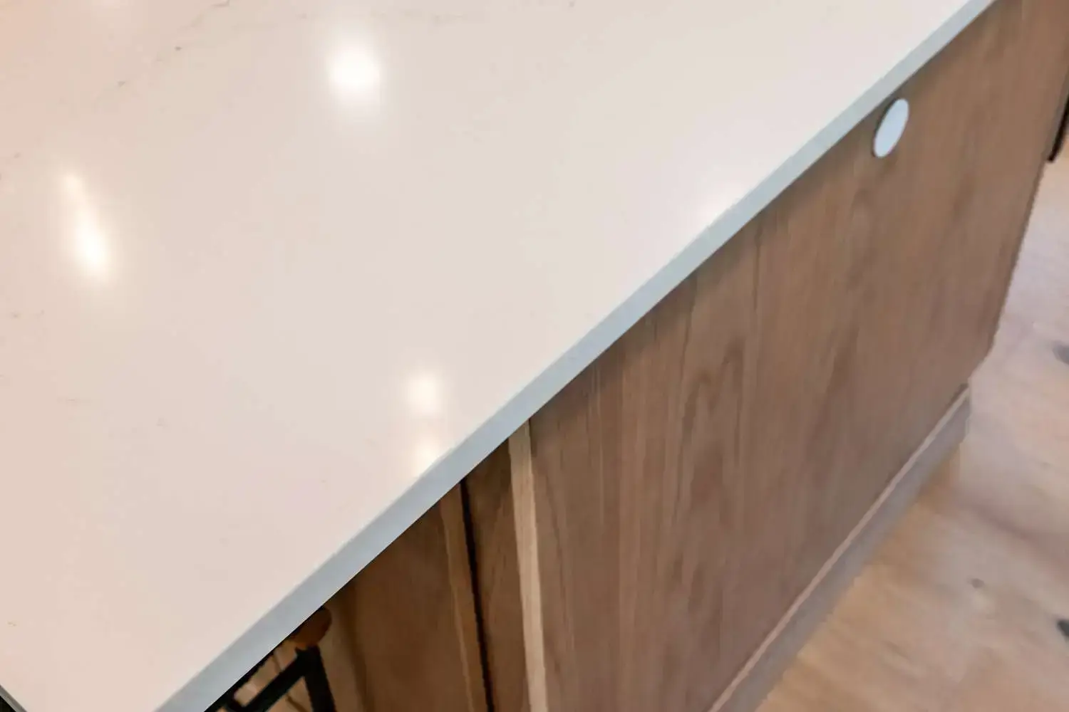 Custom kitchen countertop with a sleek white surface and warm wooden cabinetry, showcasing modern design elements for a custom home build in Exeter, NH.
