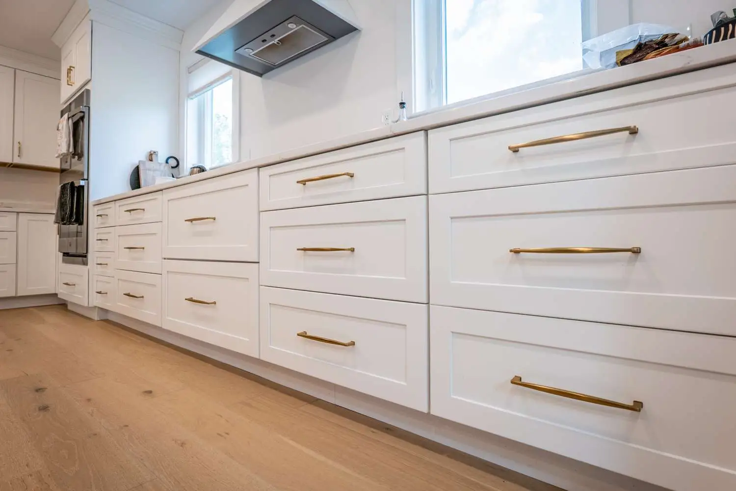 Modern kitchen with custom white cabinetry, gold handles, and light wood flooring, showcasing a clean and functional design for remodeling projects.