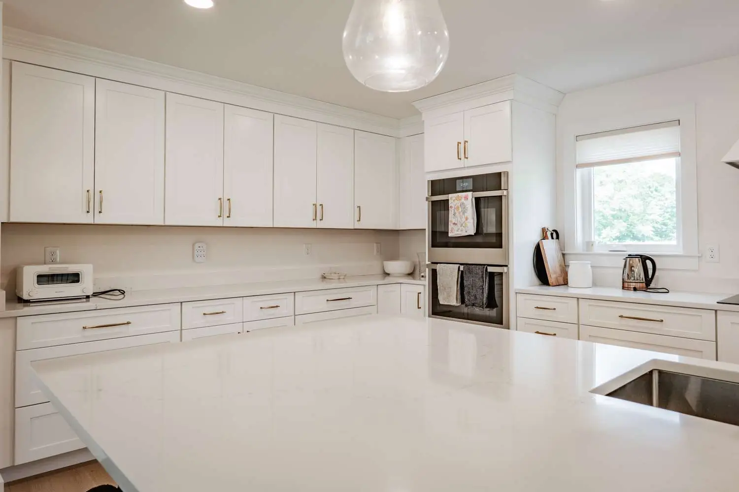 Modern kitchen featuring white cabinetry, stainless steel appliances, quartz countertops, and an open layout with a view of greenery.