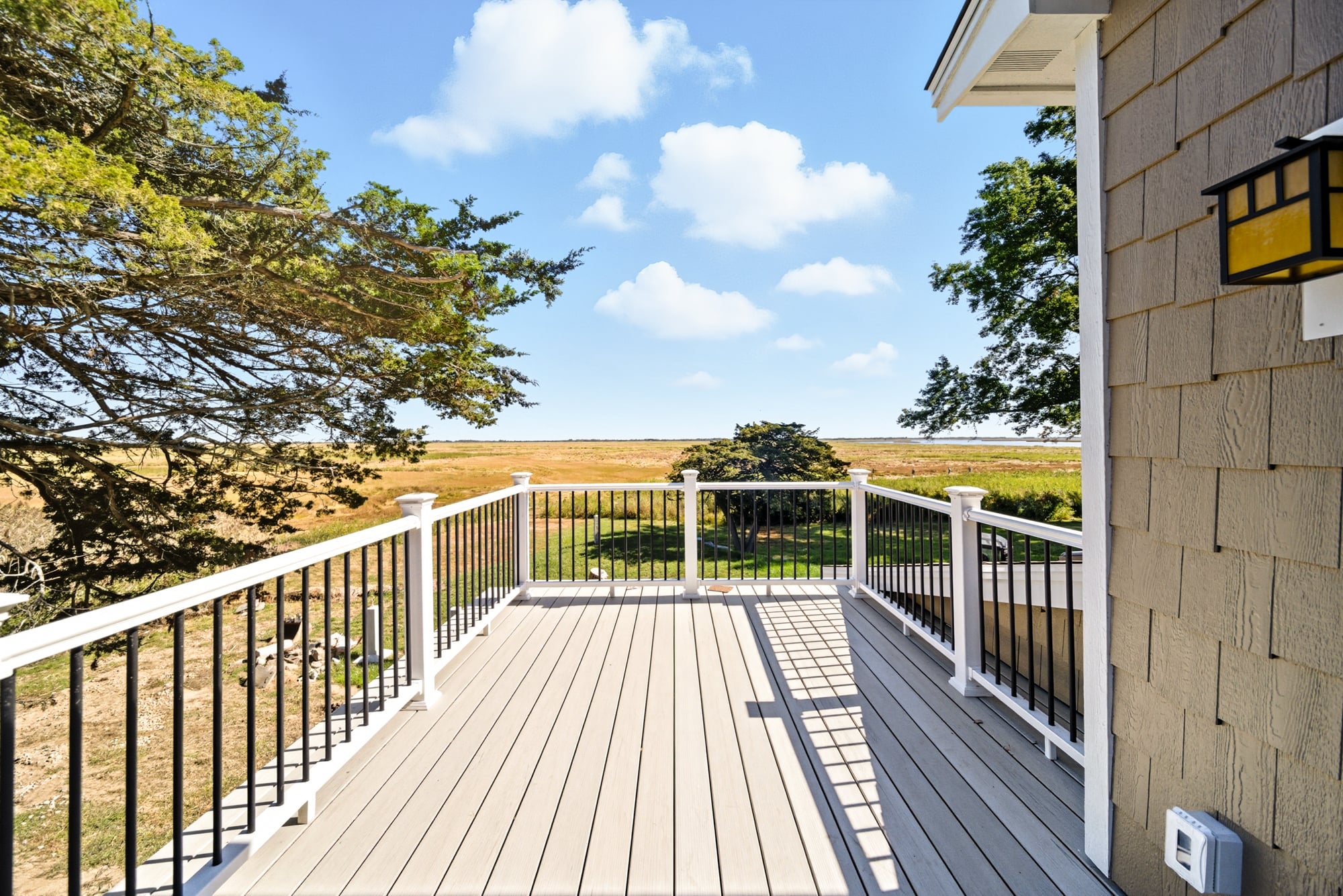 Deck featuring composite flooring and black railings overlooking marsh views, showcasing the outdoor space of a renovated home in West Newbury, MA.