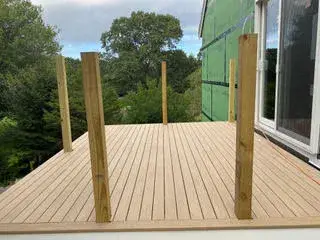 Composite deck flooring with wooden posts in Essex ADU construction, showcasing outdoor living space preparation.
