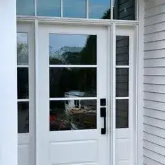White front entry door with transom and glass panels, showcasing modern design elements for the Essex ADU project.