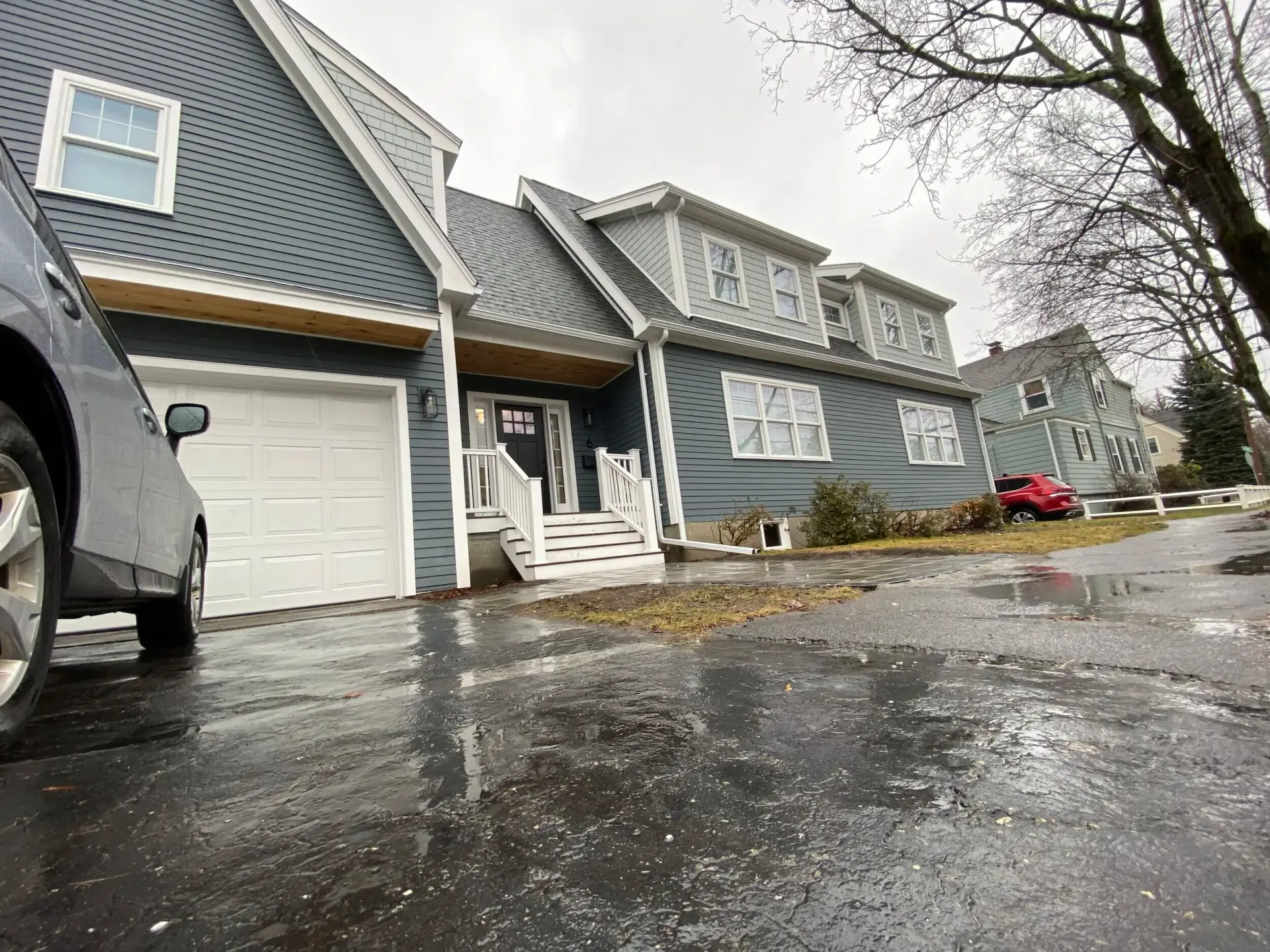 Completed custom home in Wakefield, MA with blue clapboard siding, new foundation, and driveway view featuring a garage and landscaped front yard.