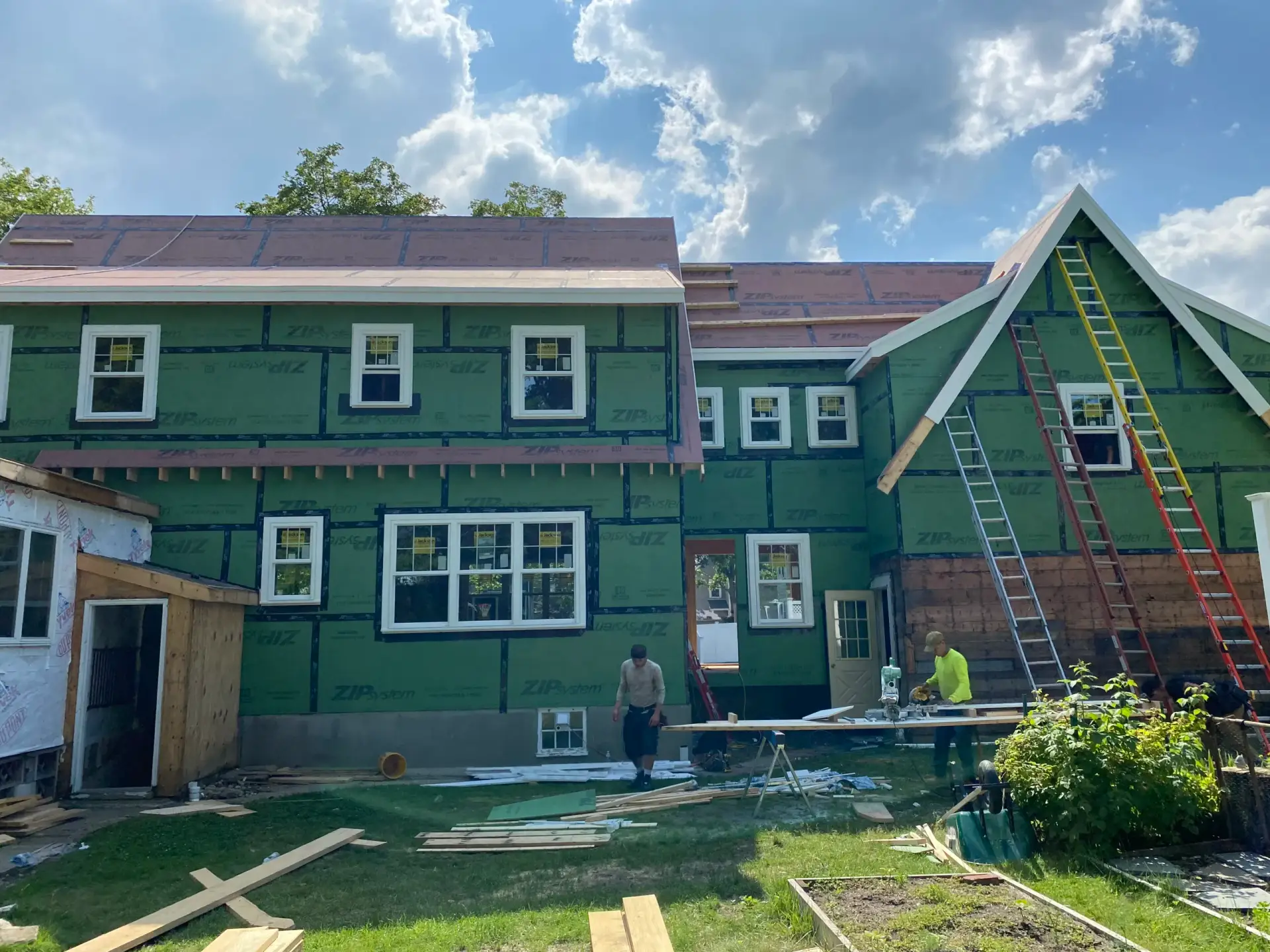 Modern custom home under construction featuring ZIP sheathing, workers on-site, and ladders against the exterior, showcasing Bradford Construction Management's design-build approach in Eastern Massachusetts.