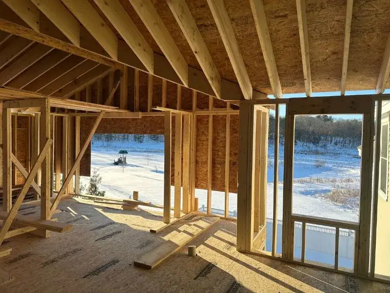 Interior view of a partially constructed garage conversion, showcasing wooden framing and natural light, with snowy landscape visible through large windows, relevant to garage-to-ADU conversion process.