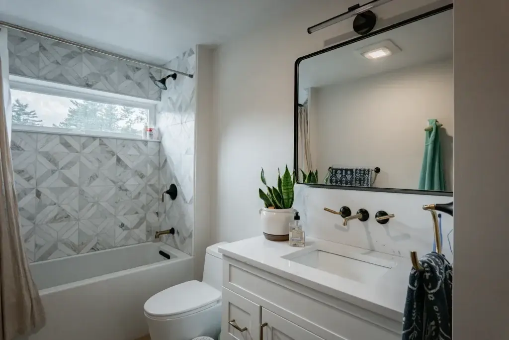 Modern bathroom featuring a bathtub with elegant tile design, a stylish mirror above a white vanity, and indoor plants, emphasizing healthy home aesthetics and indoor air quality.