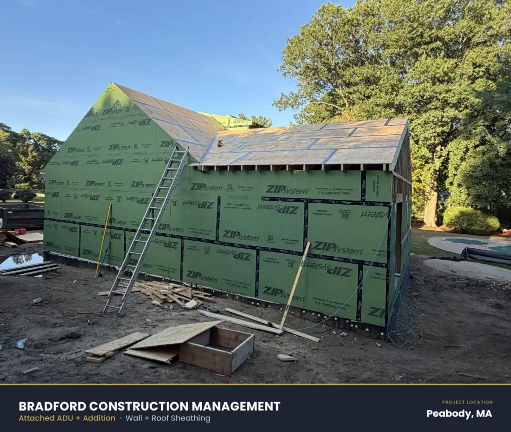 New construction site featuring an addition with roof sheathing and a ladder