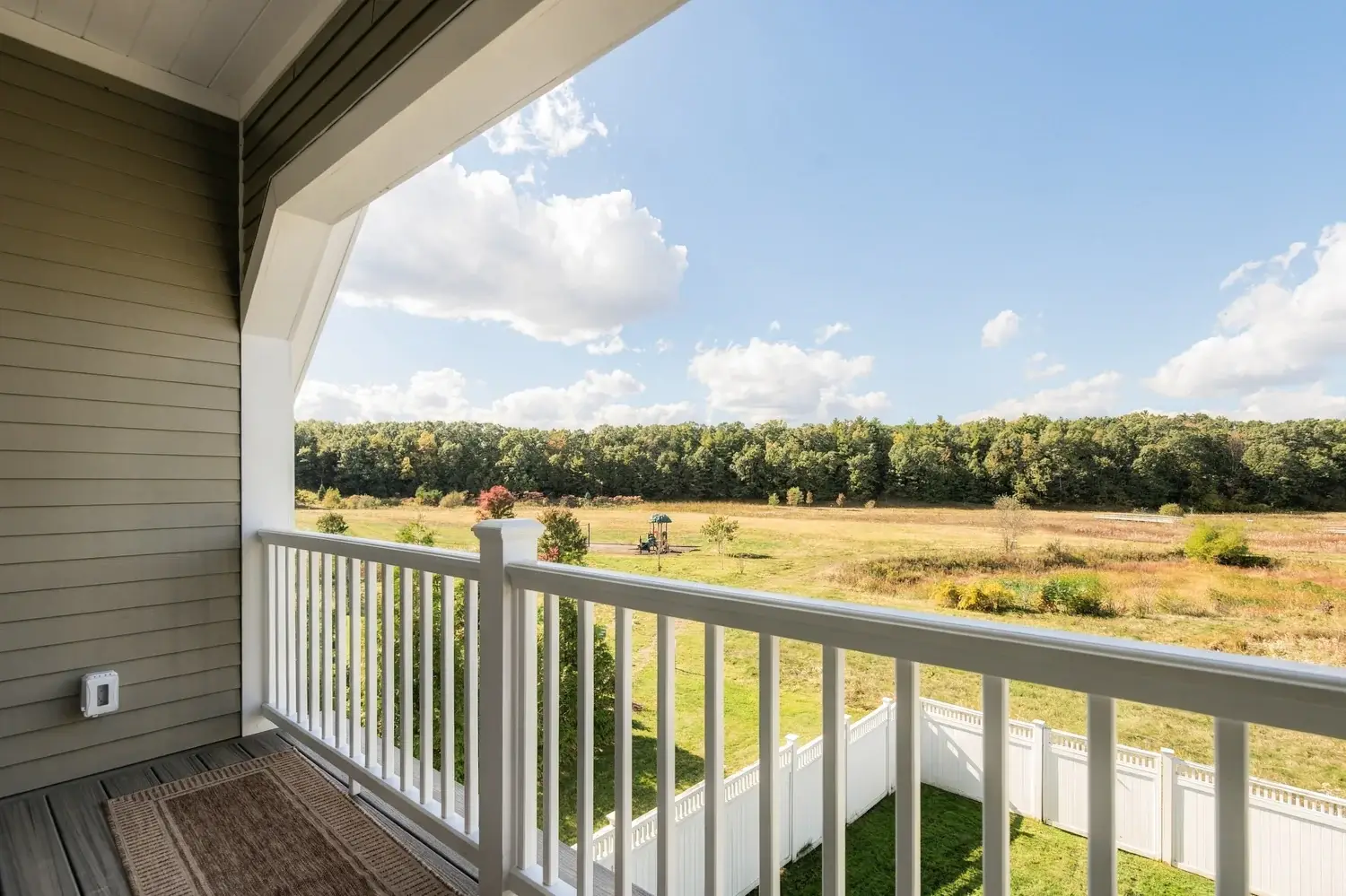Balcony railing overlooking an open field and trees