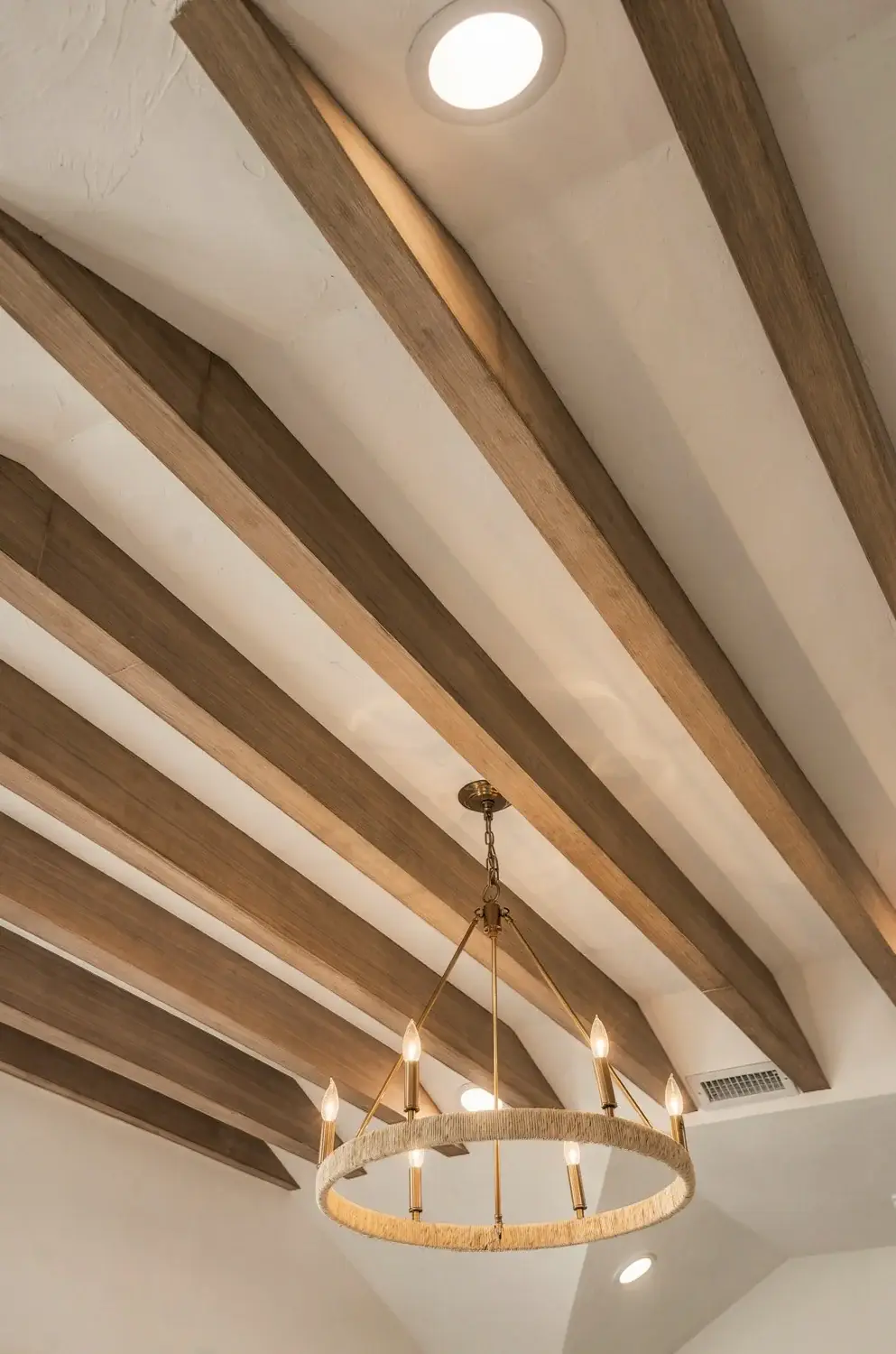 Exposed wood beams and chandelier in the primary bedroom