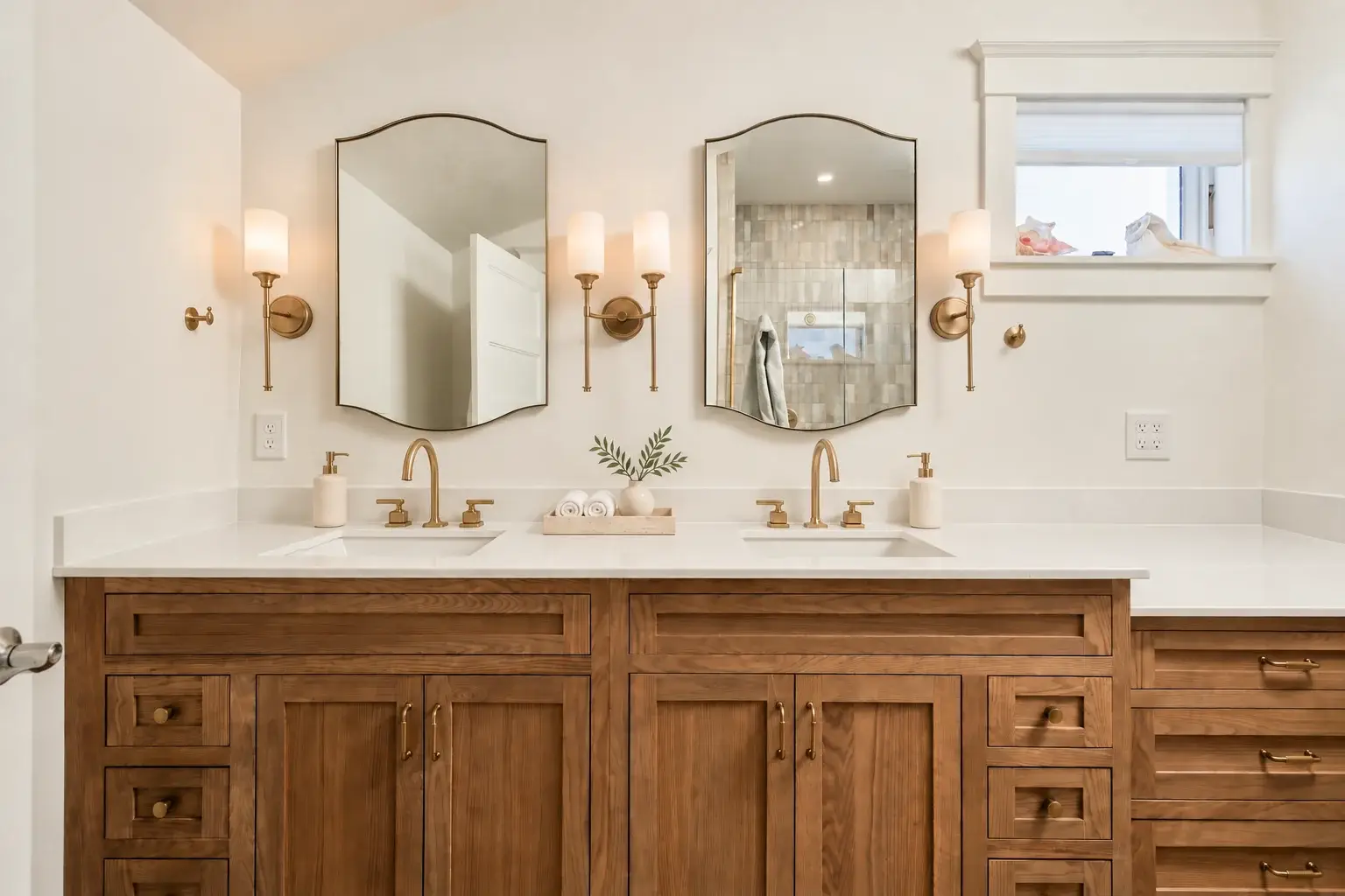 Wood double vanity, brass faucets, and paired mirrors in the finished primary bathroom